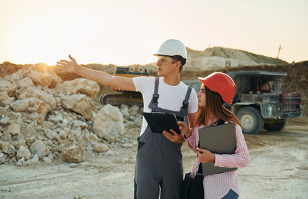 With documents. Two workers is on the borrow pit at daytime togetherの写真素材