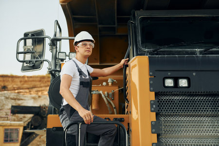 Quality vehicle. Worker in professional uniform is on the borrow pit at daytimeの写真素材