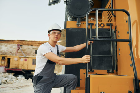 Quality vehicle. Worker in professional uniform is on the borrow pit at daytime