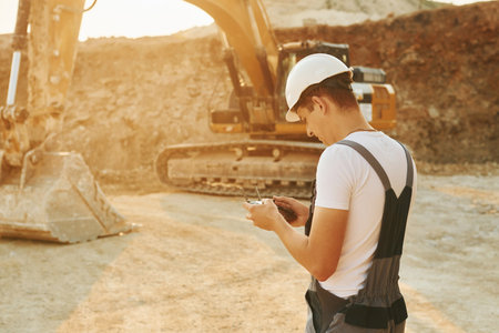 Control of the project. Worker in professional uniform is on the borrow pit at daytimeの写真素材