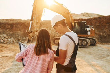 Talking about plan. Two workers is on the borrow pit at daytime togetherの写真素材