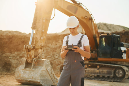 Illuminated by sunlight. Worker in professional uniform is on the borrow pit at daytimeの写真素材
