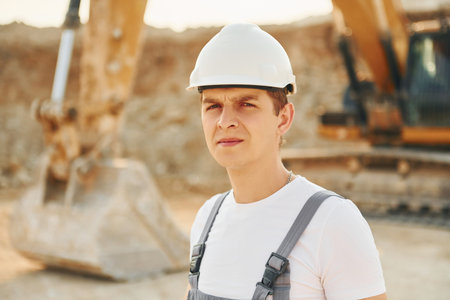 Illuminated by sunlight. Worker in professional uniform is on the borrow pit at daytimeの写真素材
