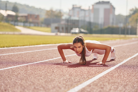 Conception of bodycare. Young woman in sportive clothes is exercising outdoorsの写真素材