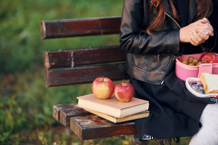 Close up view of couch with schoolgirl, books and applesの写真素材