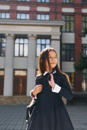 Schoolgirl is outside near school buildingの写真素材