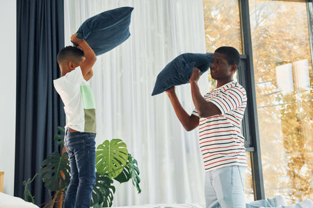 Pillow fight. African american father with his young son at home.の写真素材