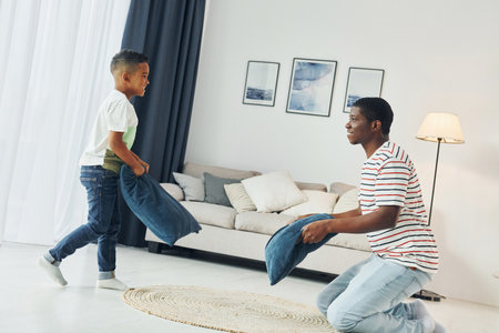 Pillow fight. African american father with his young son at home.の写真素材