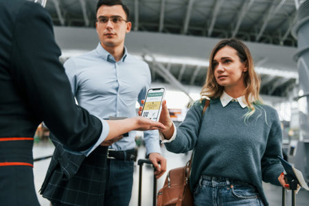 Showing vaccination certificate. Young couple is in the airport together.の写真素材