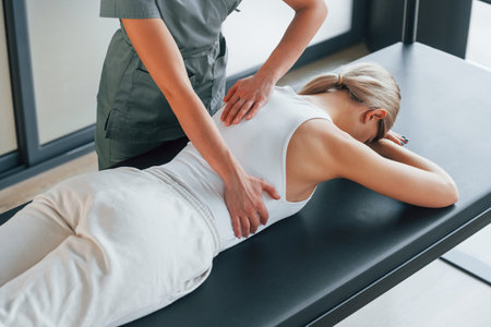 Massaging the back. Woman is in health center getting help by doctor.の写真素材
