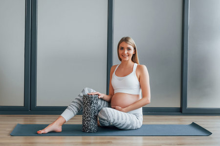 Pregnant woman in sportive clothes is in the studio.の写真素材