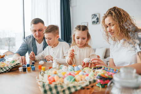 Sitting by the table. Happy family celebrating Easter holidays together.