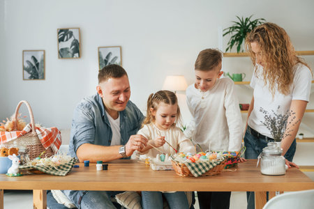 Sitting by the table. Happy family celebrating Easter holidays together.
