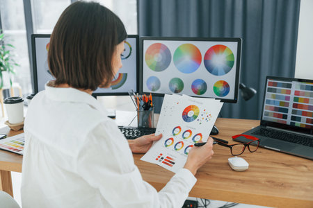 With paper. Female designer working in the office by using PC.の写真素材