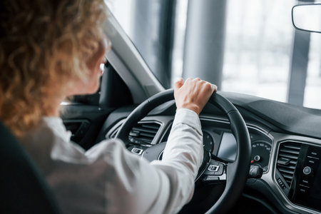 Rear view. Woman with curly blonde hair is in autosalon.の写真素材