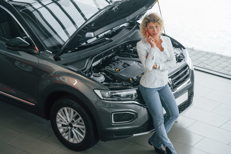Woman with curly blonde hair is in autosalon.