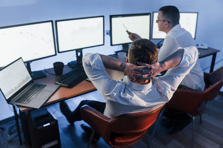 Talking with each other. Two stock traders working in the office with exchange technology.