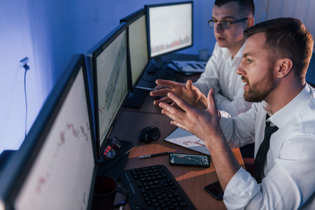 In official clothes. Two stock traders working in the office with exchange technology.