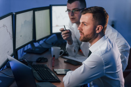 Money investment. Two stock traders working in the office with exchange technology.