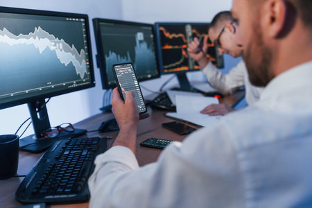 Using the phone. Two stock traders working in the office with exchange technology.