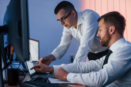 Side view. Two stock traders working in the office with exchange technology.