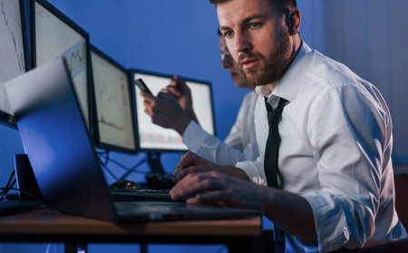 Busy day. Two stock traders working in the office with exchange technology.