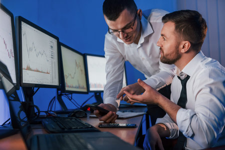 Making profit. Two stock traders working in the office with exchange technology.