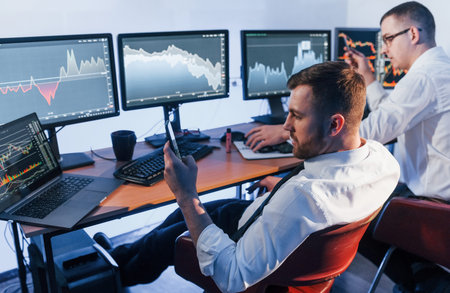 Money investment. Two stock traders working in the office with exchange technology.