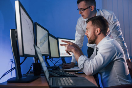 In formal clothes. Two stock traders working in the office with exchange technology.