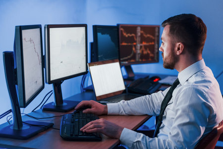 Many of the monitors. Stock trader working in the office with exchange technology.