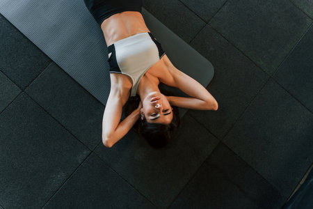 Top view. Woman in sportive clothes with slim body type is in the gym.