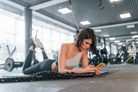 At daytime. Woman in sportive clothes with slim body type is in the gym.