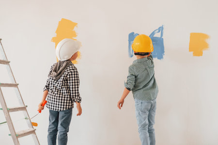 Conception of renewal. Two boys painting walls in the domestic room.