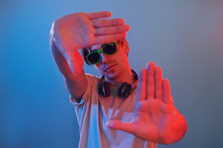 Showing gestures. Man standing in the studio with neon light.