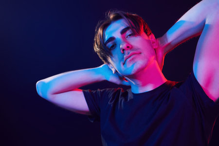 Feeling relaxed. Man standing in the studio with neon light.