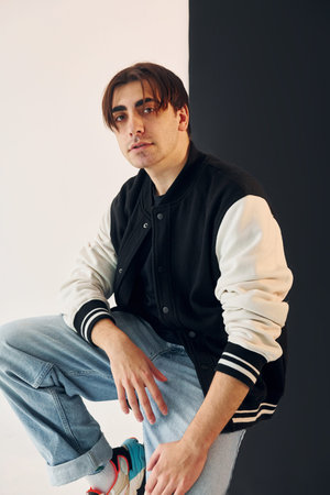 Young man is in the studio with white and black walls.