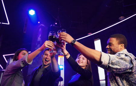 Knocking glasses. Group of friends having fun in the night club together.