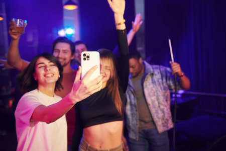 Artificial blue lighting. Group of friends having fun in the night club together.の写真素材