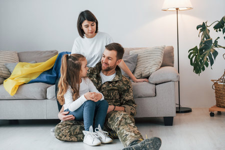 With Ukrainian flag. Soldier in uniform is at home with his wife and daughter.の写真素材