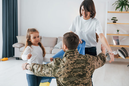 Ukrainian's hard times. Soldier in uniform is at home with his wife and daughter.