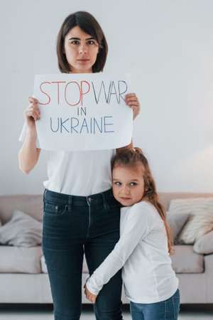 Mother with her little daughter standing with banners with text stop war in Ukrane.
