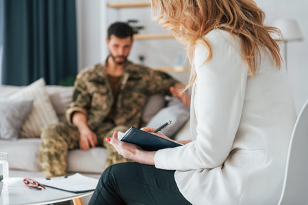 Talking to doctor. Soldier have therapy session with psychologist indoors.の写真素材