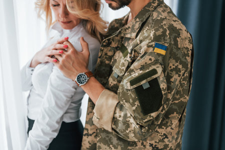 Flag of Ukraine. Soldier with his wife standing indoors and embracing.の写真素材