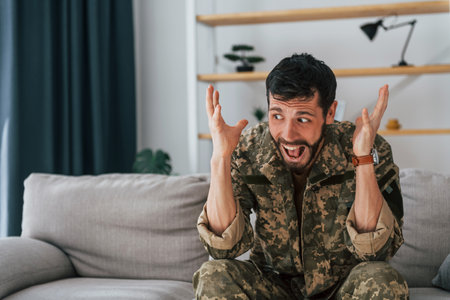 Soldier in uniform is indoors in the domestic room.の写真素材