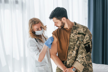 Soldier get vaccinated by female doctor indoors.の写真素材