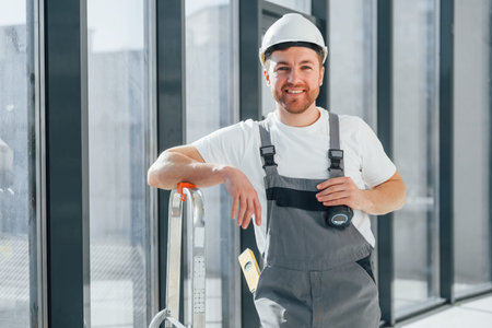 Smiling and posing. Repairman is working indoors in the modern room.