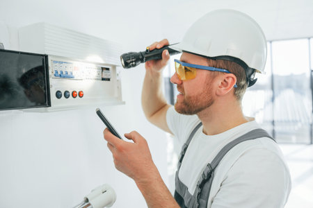 Electricity problems. Repairman is working indoors in the modern room.