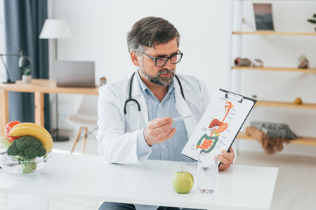 Man is showing illustration. Conception of dieting. Professional medical worker in white coat is in the office.の写真素材