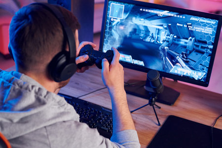 Using the joystick. Online streamer playing FPS shooter game at home.