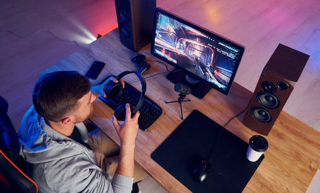 Top view. Online streamer playing FPS shooter game at home.